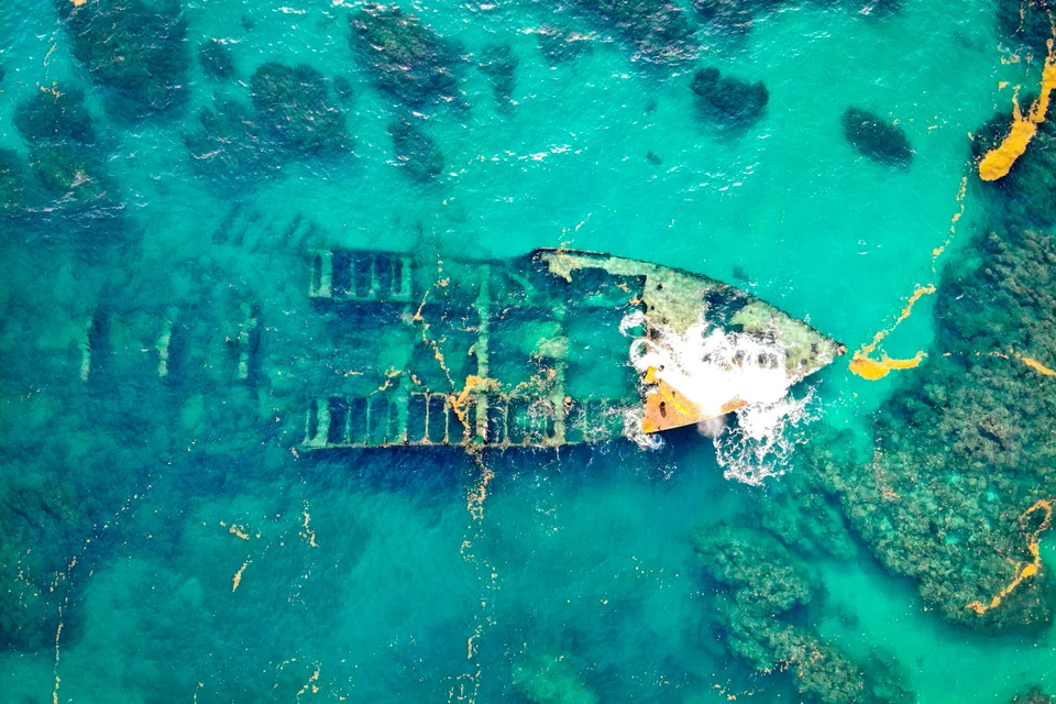 Aerial view of a shipwreck in shallow turquoise water